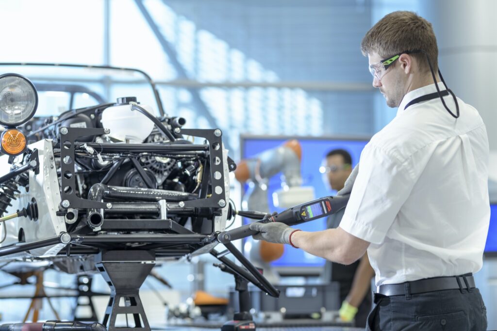 Engineer using computerised tools to assemble car in robotics research facility